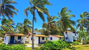 A resort with white buildings, palm trees, and a hammock. - Pousada Les Alizes (Amontada)