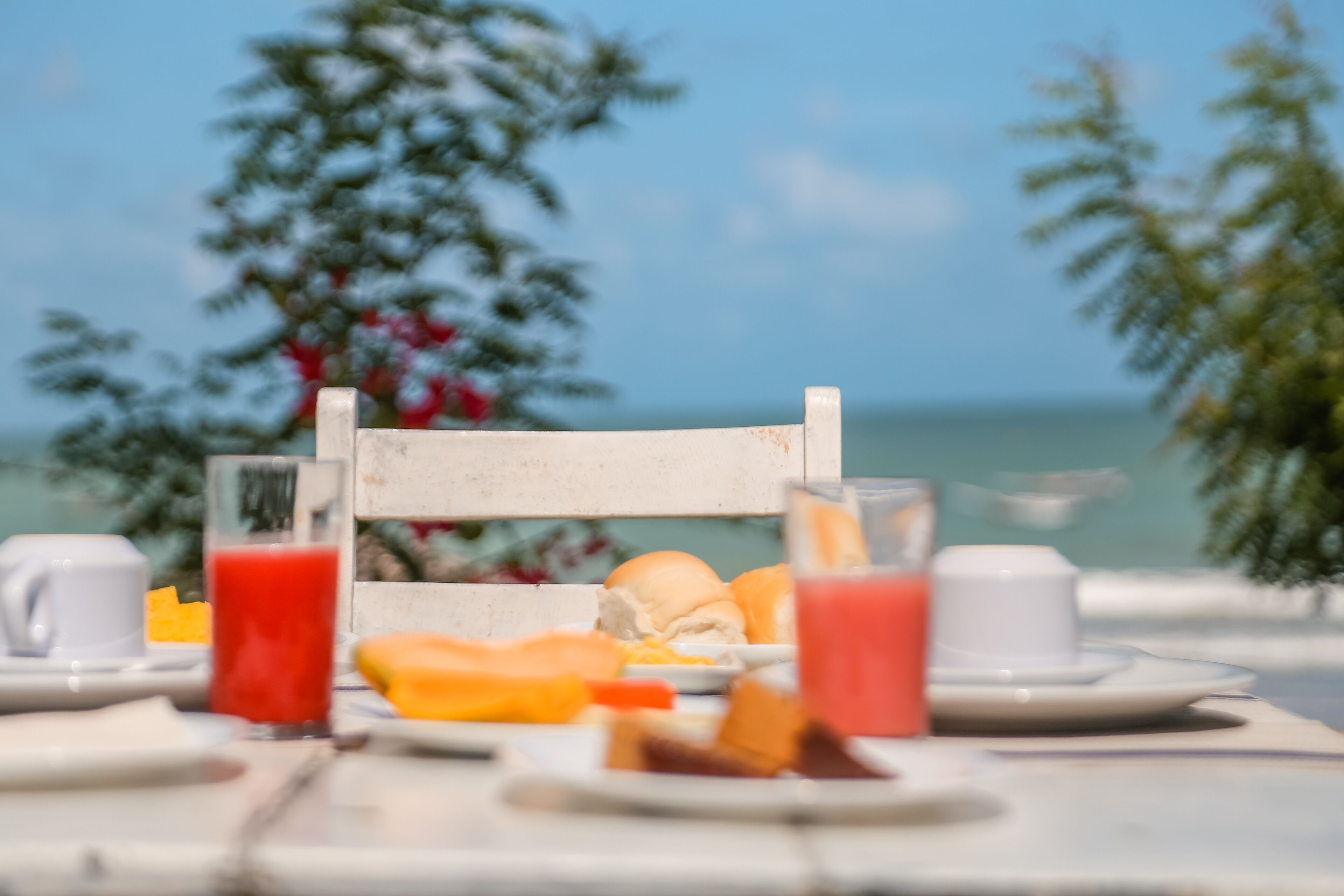 A table set for breakfast with a view of the sea and trees in the background.