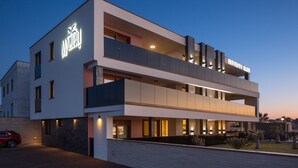 Un hotel moderno con un letrero llamativo, varios balcones y una fachada bien iluminada.