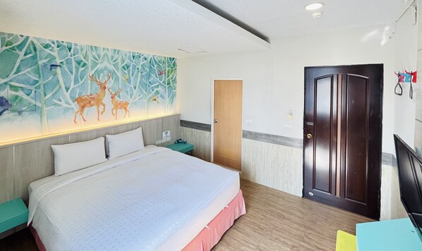 Quarto de hotel com cama grande, mesa de cabeceira, porta de madeira e um mural de veados na parede.