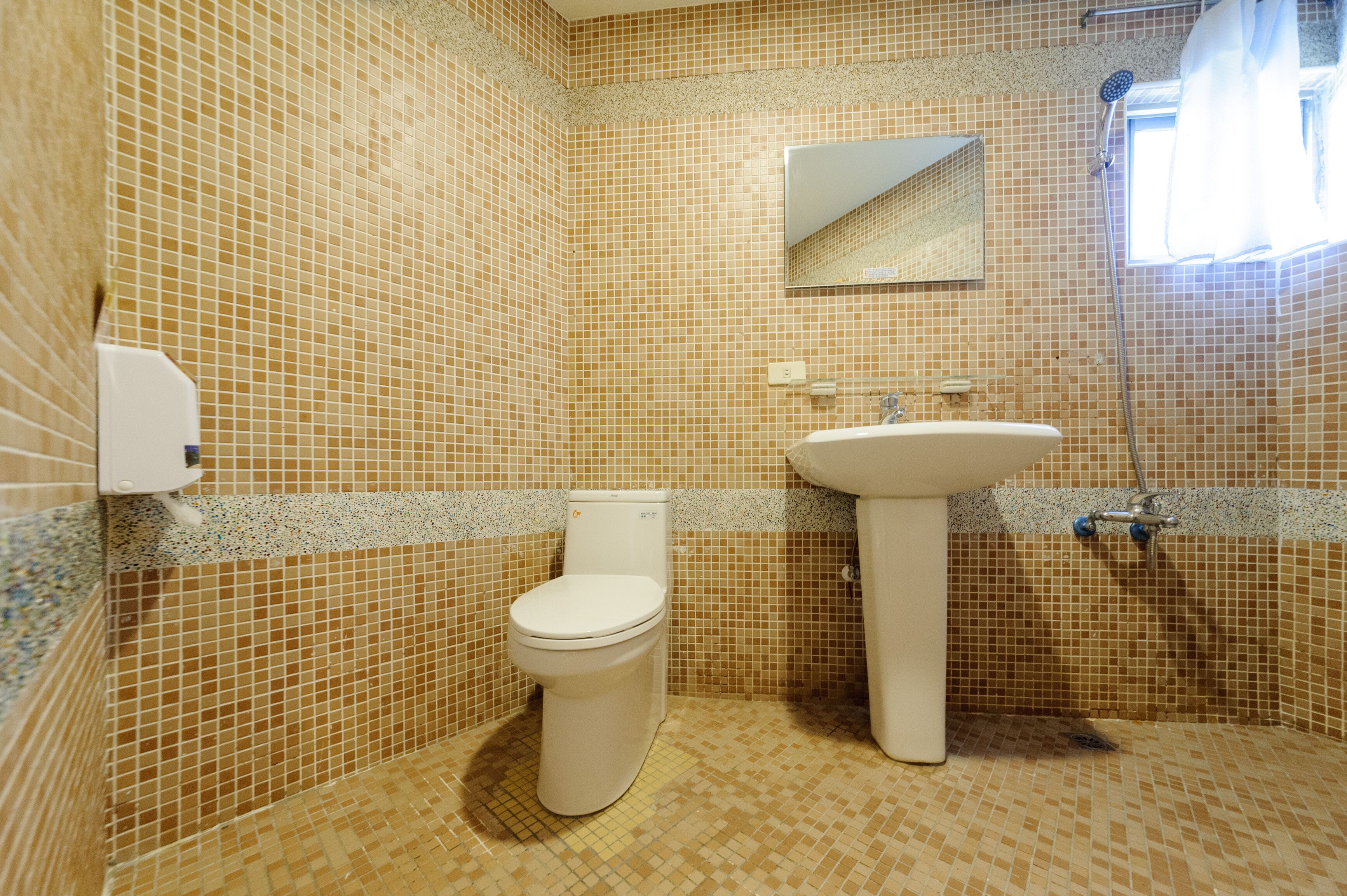 Et badeværelse med toilet, vask og brusebad.