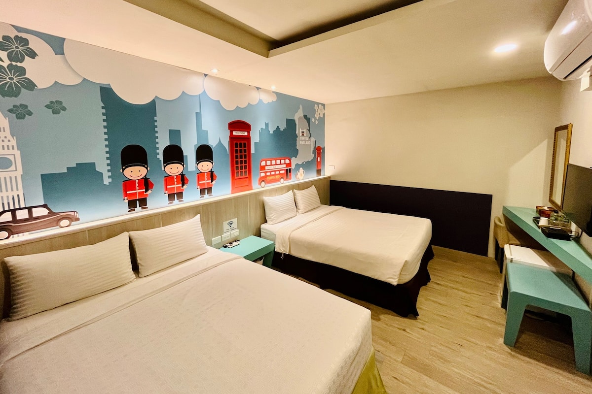 A hotel room with two beds, a desk, and a wall mural depicting London landmarks.