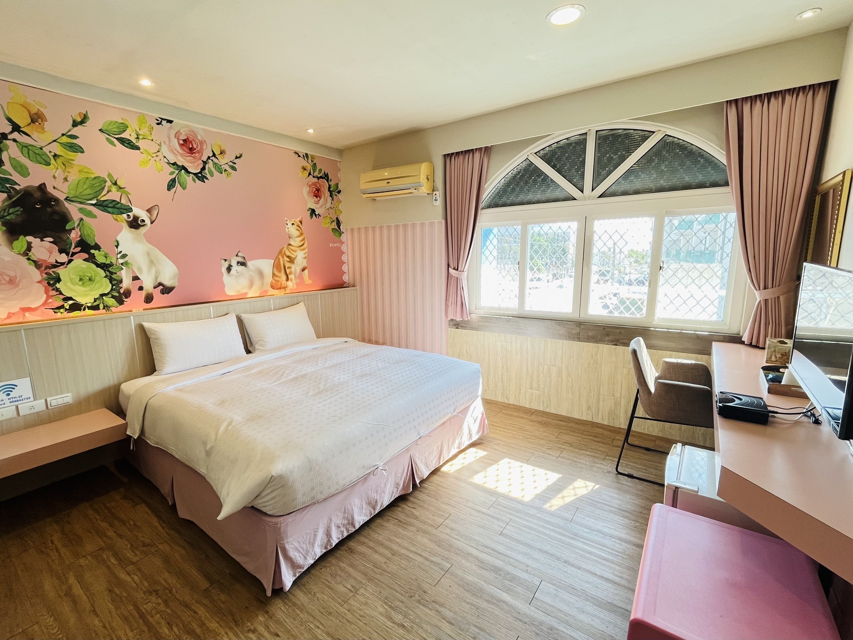 Un dormitorio con cama, escritorio y ventana con cortinas.