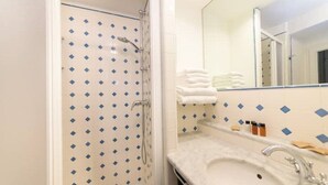A bathroom with a shower, a sink, and a mirror.