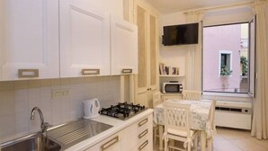 A kitchen with white cabinets, a gas stove, a sink, and a dining table with chairs.