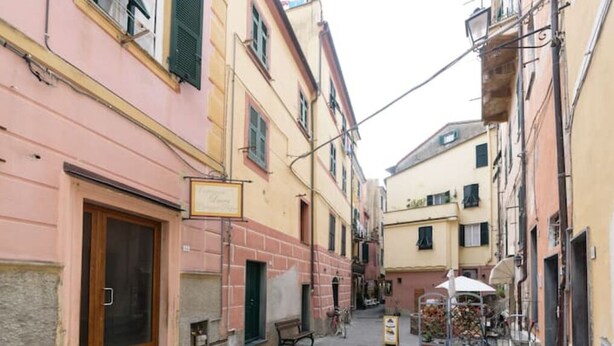 A narrow street with buildings on both sides, a wooden door on the left, and a bicycle parked on the right. - Carla House - Monterosso Cinque Terre .- Citra011019-LT-0135 (Monterosso al Mare)