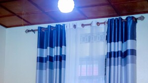 A room with a window covered by blue and white striped curtains, a wooden ceiling, and a visible window frame. - Inviting 6-bedrooms Apartment in Kigali (Kigali)