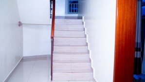 A staircase with white walls and a wooden handrail leading to a landing. - Inviting 6-bedrooms Apartment in Kigali (Kigali)