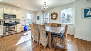A modern kitchen with stainless steel appliances, a dining area with wicker chairs, and a view of the city through large windows.