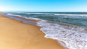 Una spiaggia con cieli azzurri e onde che lambiscono dolcemente la riva.
