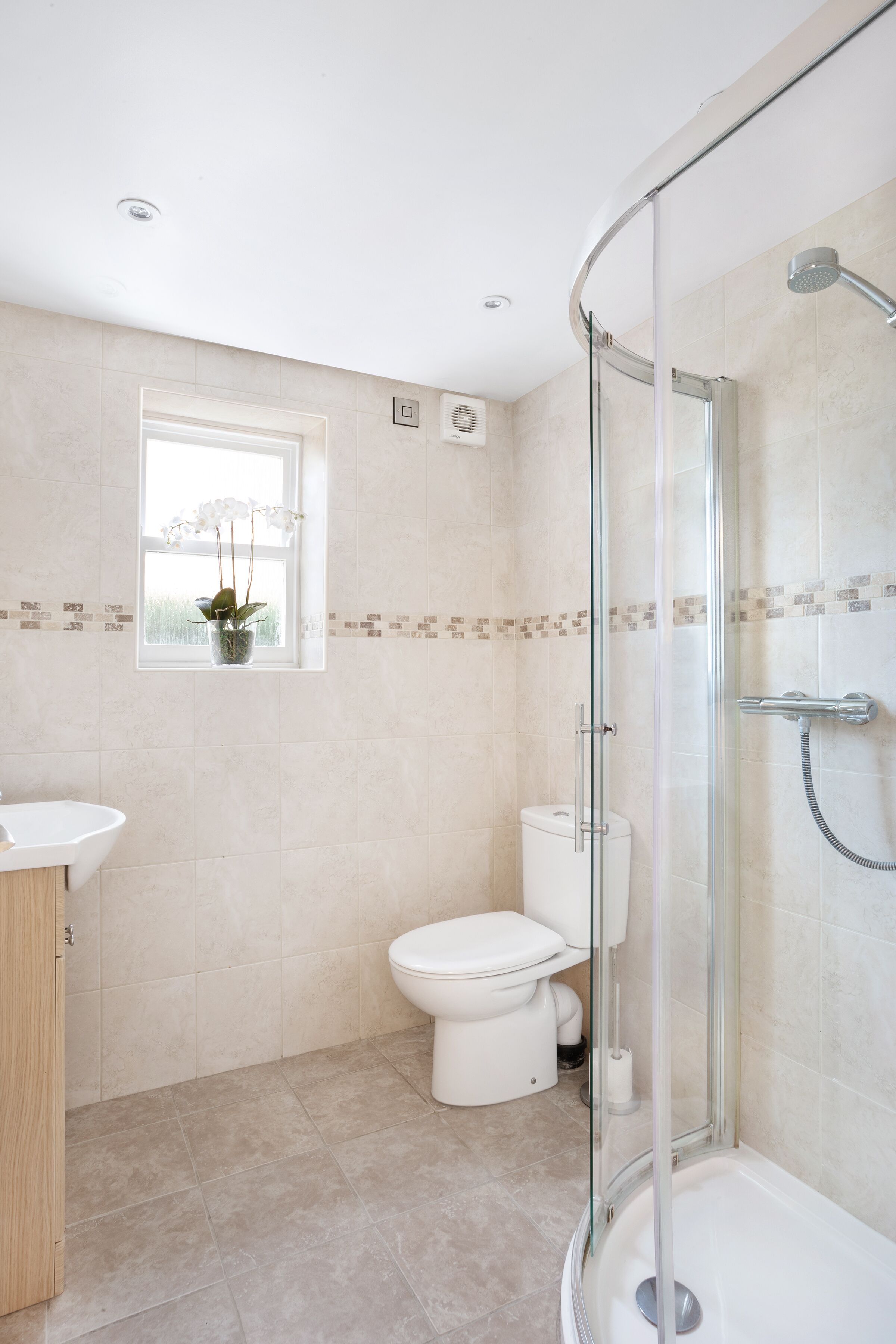 A modern bathroom with a glass-enclosed shower, a toilet, and a sink.