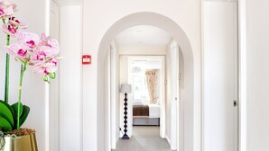 Ein Flur mit Teppichboden, weißen Wänden und einer gewölbten Tür, die in ein Schlafzimmer führt.