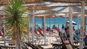 Ein Strand mit gestreuten Sonnenschirmen und Liegestühlen.