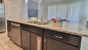A modern kitchen with granite countertops, stainless steel appliances, and pendant lighting.