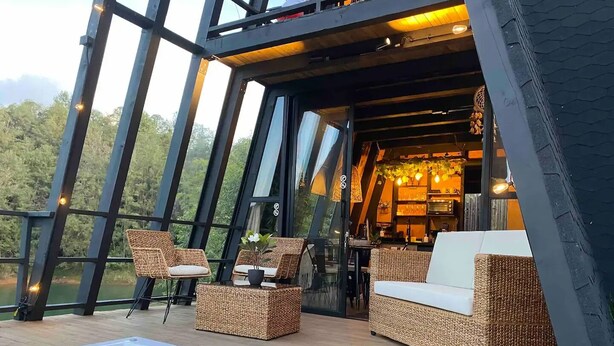 A modern outdoor lounge area with wicker furniture, a hot tub, and a bar area with warm lighting. - Unique Lake House breathtaking views (Guatape)
