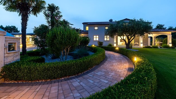 A well-maintained garden with a curved brick pathway leading to a building with multiple windows and a tiled roof. - Charming Villa Filton with swimming pool, sauna and jacuzzi (Markovici)
