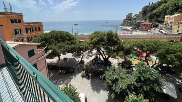 A coastal town with buildings, trees, and a view of the sea. - Virginia House - CITRA 011019-LT-0354 (Monterosso al Mare)