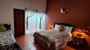 Un dormitorio con dos camas, una ventana con cortinas, una lámpara de pared y un adorno con forma de corazón.