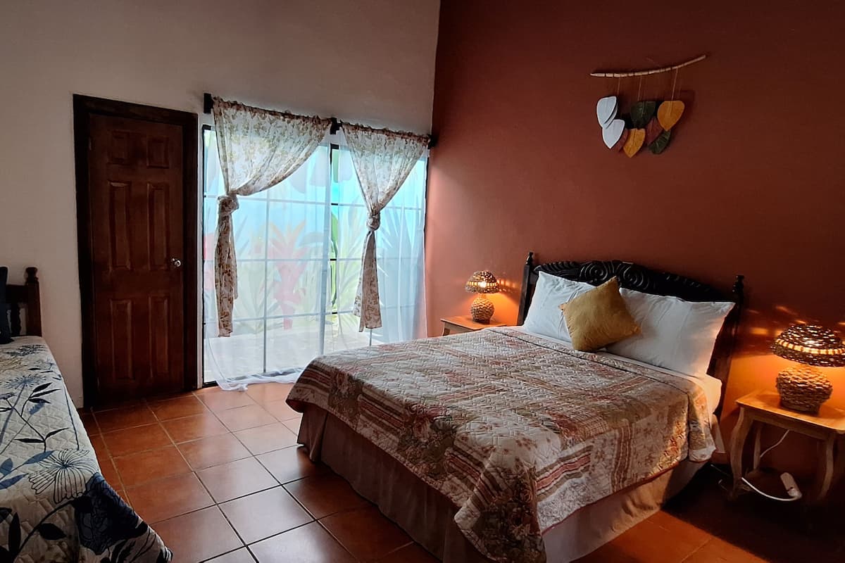 Un dormitorio con dos camas, una ventana con cortinas, una lámpara de pared y un adorno con forma de corazón.