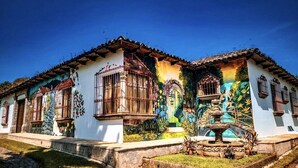 Un edificio tradicional con tejado de baldosas, múltiples ventanas y una fuente decorativa en el patio.