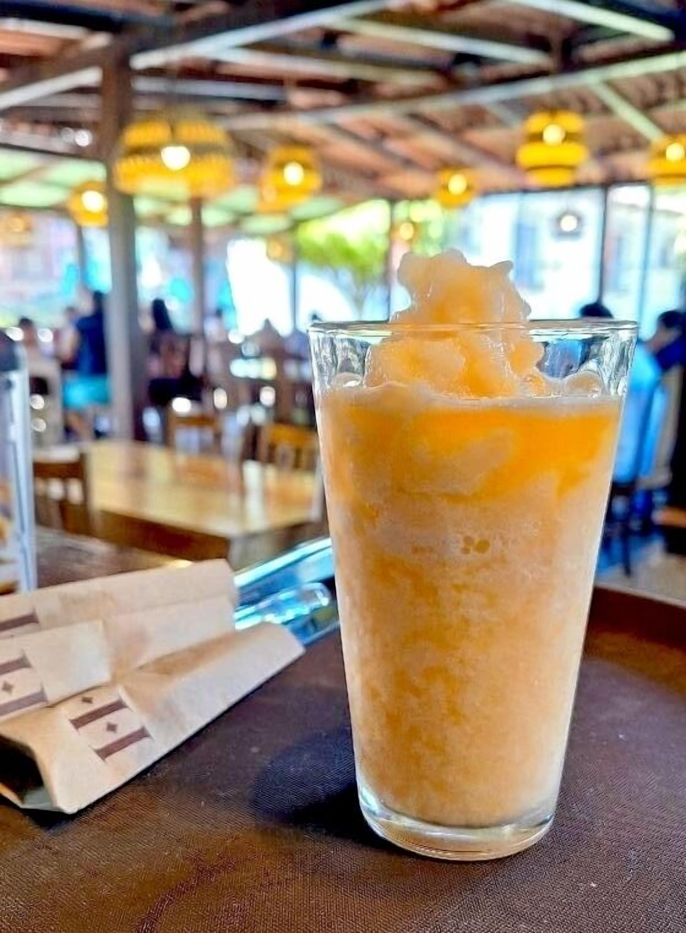 A glass of iced coffee with ice cubes on a table in a restaurant.