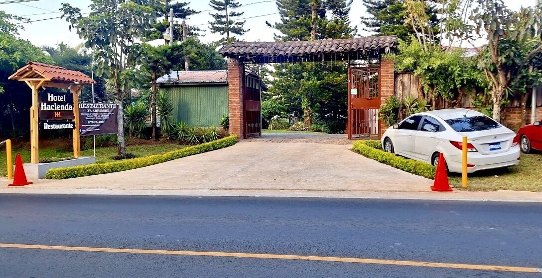 Entrada com portão para um hotel, com sinalização indicando que possui restaurante.