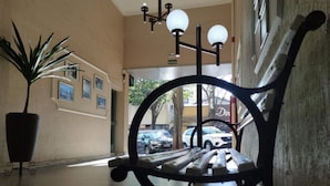 A hallway with a bench, a potted plant, and a view of the street outside. - Smart Cataratas Hotel (Foz do Iguaçu)