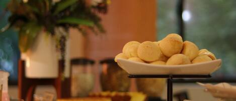 A buffet with various food items, including a plate of round pastries, a bowl of fruit, and a variety of other dishes.