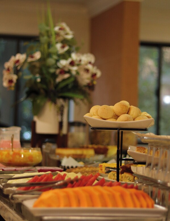 A buffet with various food items, including fruits and pastries, arranged on a buffet stand.