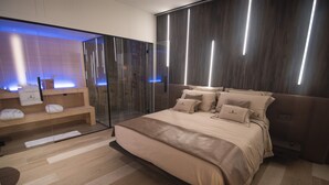 A modern bedroom with a large bed, a glass shower enclosure, and a wooden floor. - Tritone Luxury Suites Fontana di Trevi (Rome)
