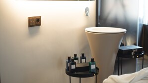 A modern bathroom with a large sink, a mirror, and a small table with toiletries. - Tritone Luxury Suites Fontana di Trevi (Rome)