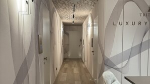 A modern hallway with patterned walls, a wooden floor, and a table with chairs. - Tritone Luxury Suites Fontana di Trevi (Rome)