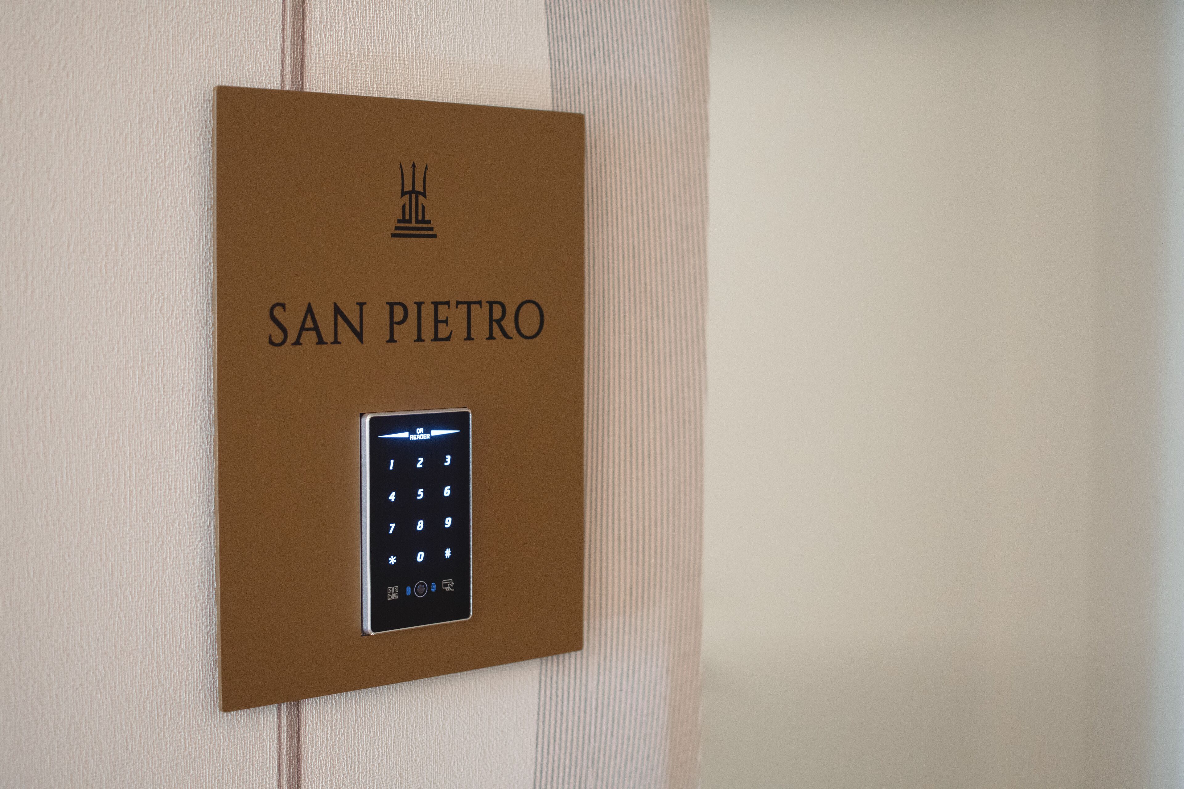 Painel de comando de elevador fixado na parede, com o nome "SAN PIETRO" e um teclado numérico.