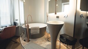 A modern bathroom with a freestanding bathtub, a large mirror, and a sleek vanity. - Tritone Luxury Suites Fontana di Trevi (Rome)