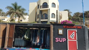 A building with a sign reading "WINDSURFING SUP" and a surfboard displayed outside.