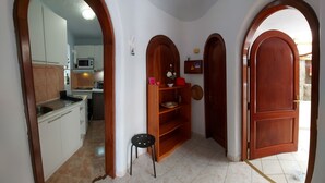 A narrow hallway with wooden doorways leading to a kitchen area.