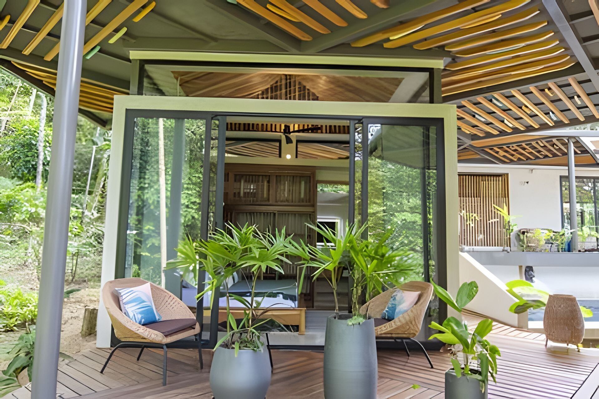 A modern outdoor seating area with wooden flooring, cushioned chairs, and potted plants.
