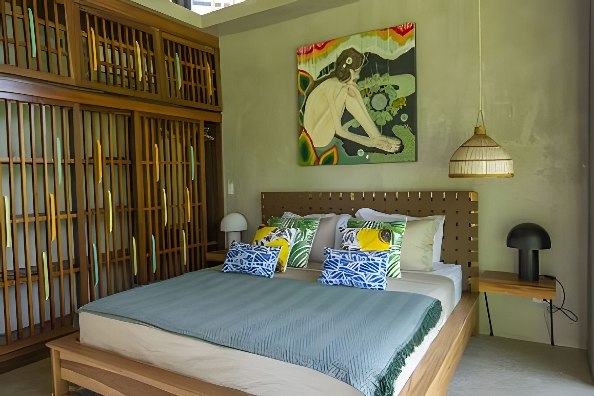 Un dormitorio con cama, cabecero de madera, un cuadro y una lámpara colgante.