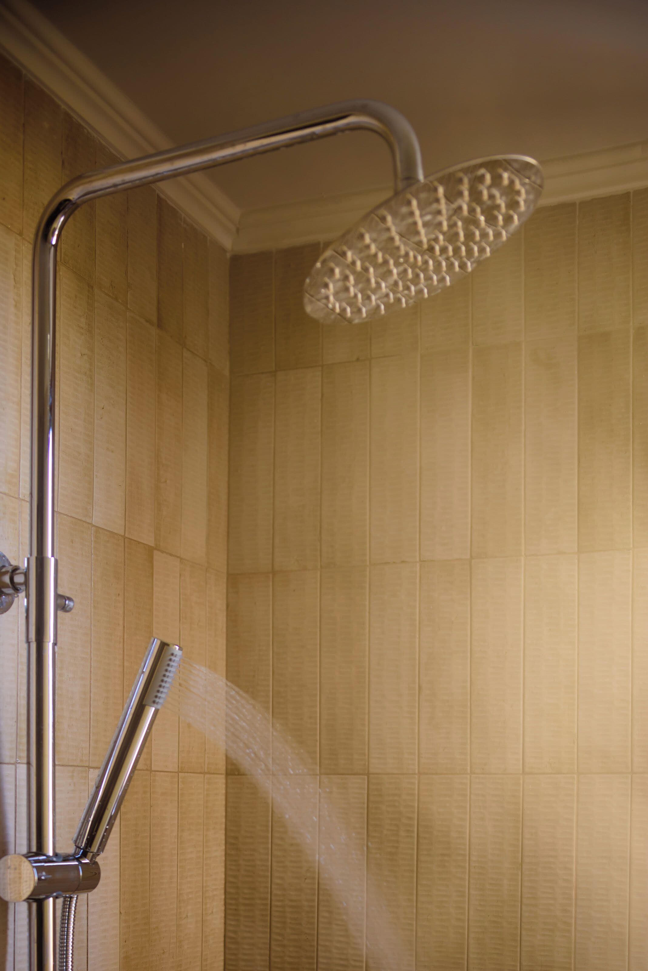 A shower with a handheld showerhead and a fixed overhead showerhead.
