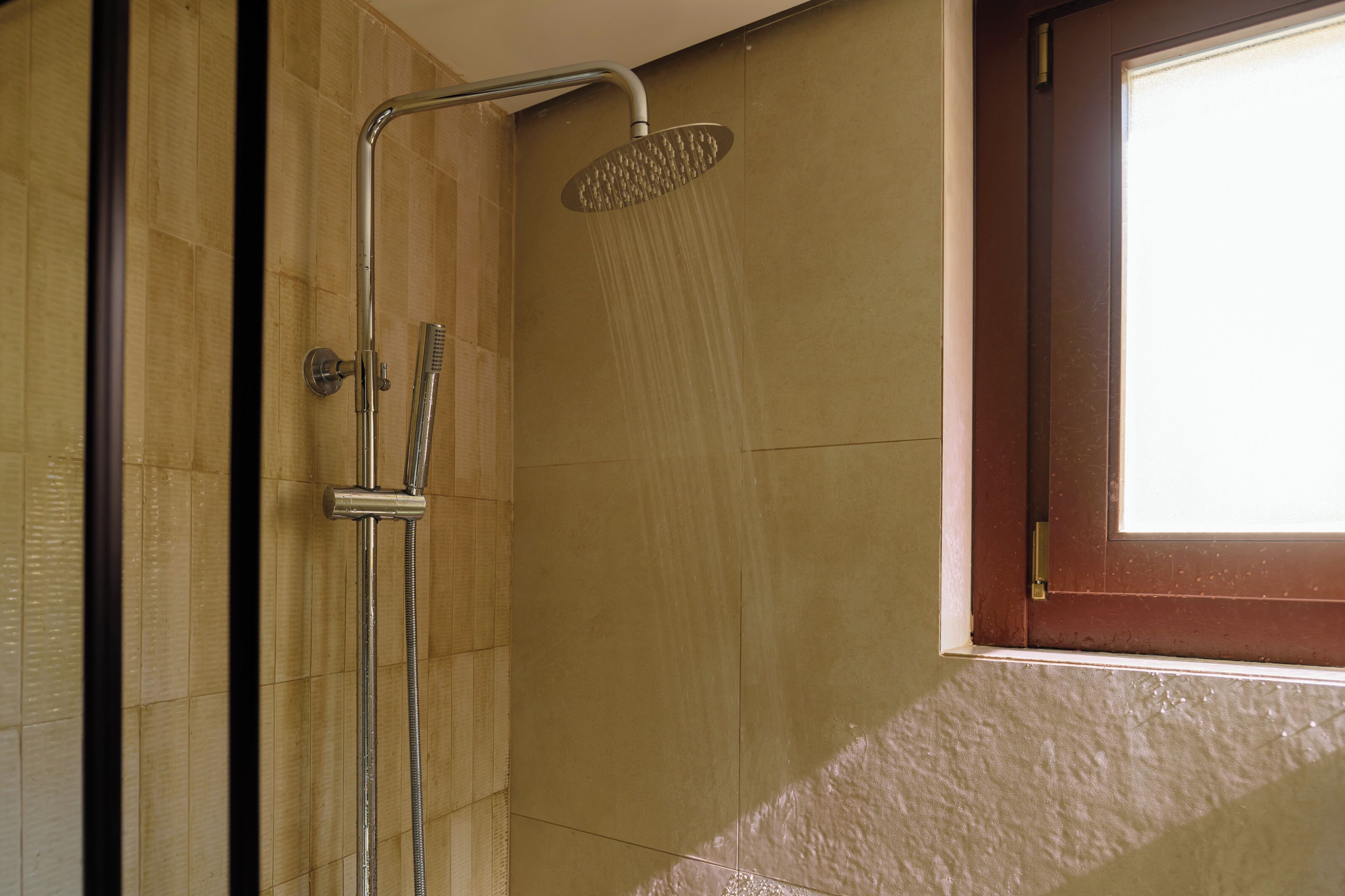 A shower with a handheld showerhead and a wall-mounted faucet.