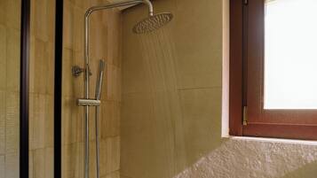 A shower with a handheld showerhead and a wall-mounted faucet.