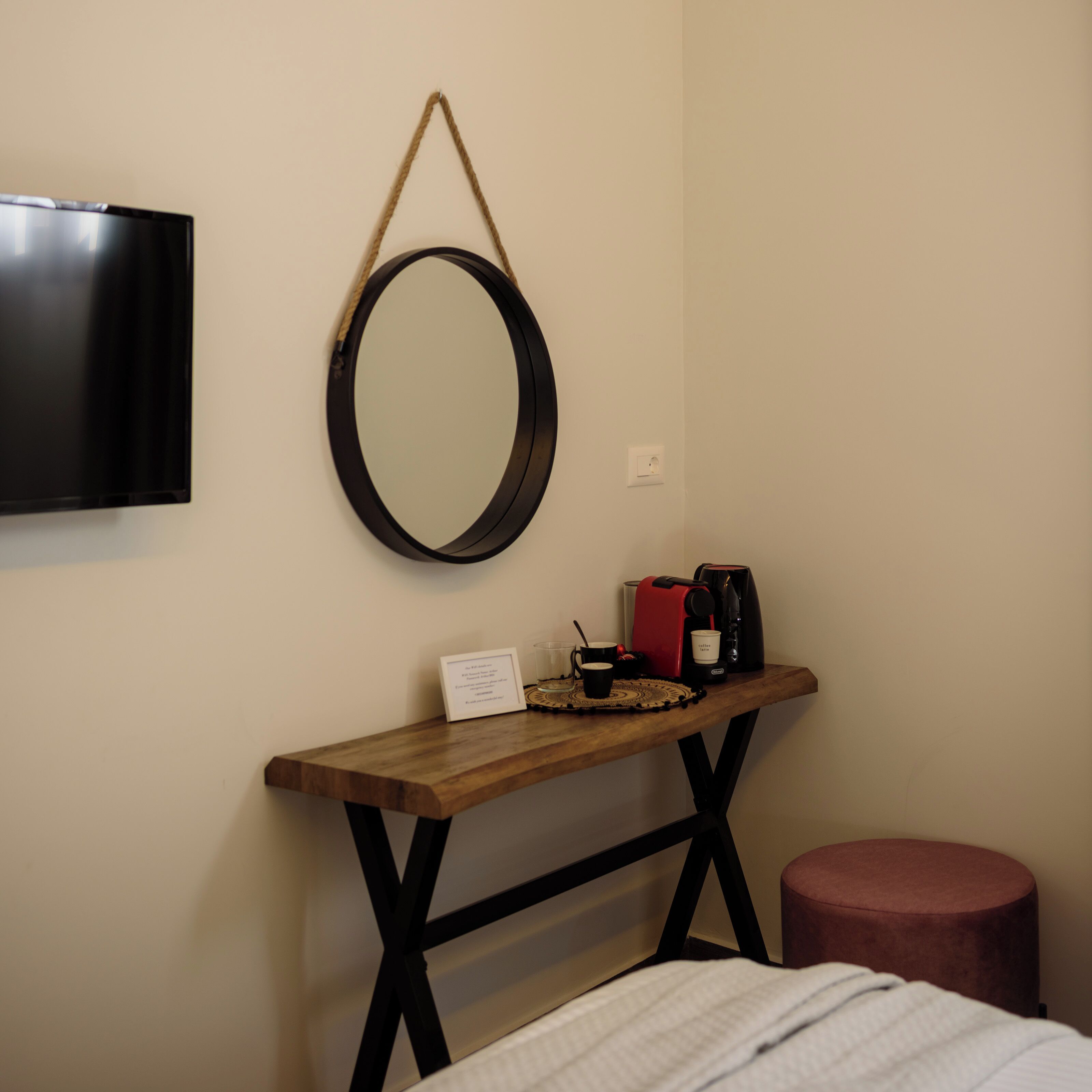 A room with a wooden console table, a coffee maker, a cup, and a sign.