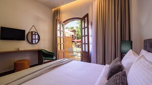 Ein Hotelzimmer mit Bett, Schreibtisch, Flachbildfernseher, Stuhl und Blick ins Freie.