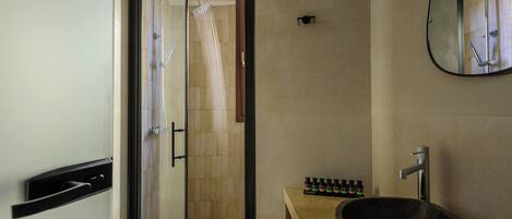 A modern bathroom with a glass-enclosed shower, a large stone sink, and a mirror above the sink.