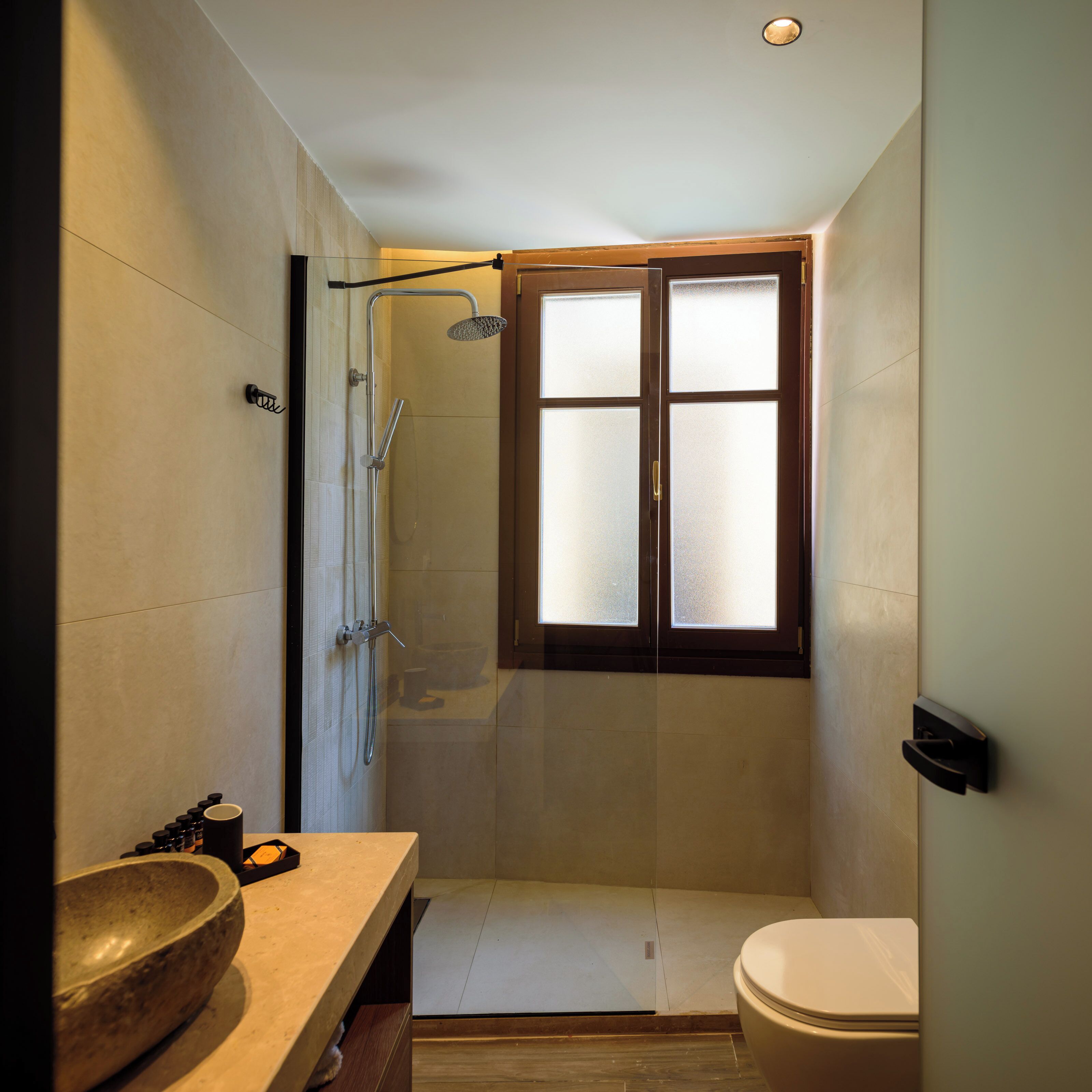 Une salle de bain compacte comprenant une douche, des toilettes et un grand lavabo.