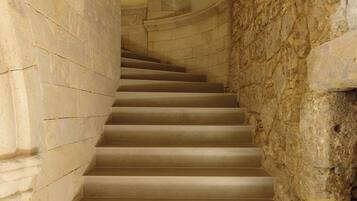 Un escalier en pierre, avec un mur en pierre d’un côté et un mur recouvert de carreaux de l’autre, mène à un niveau supérieur.