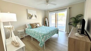 A bedroom with a bed, a desk, a ceiling fan, a window with curtains, and a plant. - Spacious 3-bedroom condo steps away from every thing in Ocean City! (Ocean City)