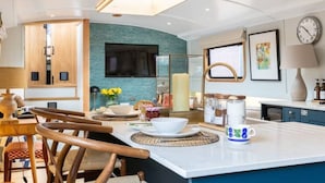 A modern kitchen with a central island, wooden cabinets, and a teal accent wall. - Luxurious houseboat in London (London)