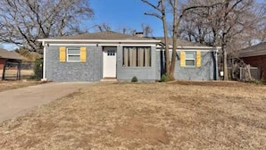 A single-story house with a gray exterior and yellow window shutters. - Charming Village Haven (Village)