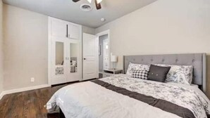 A bedroom with a bed, a ceiling fan, a wardrobe, and a nightstand. - Charming Village Haven (Village)